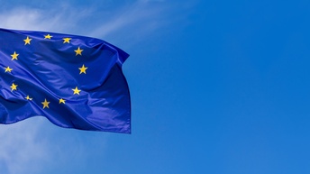 Flagge der Europäischen Union im Wind wehend, im Hintergrund blauer Himmel